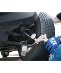 Mechanic using hand vacuum pump for brake bleeding on vehicle wheel.