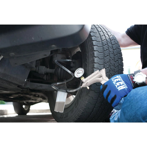Mechanic using hand vacuum pump for brake bleeding on vehicle wheel.