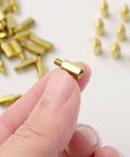 Close-up of hand holding M3 Brass Hex Standoff Spacers Set For PC Build And Motherboard 50 Pieces With Male To Female Threads 9mm And 4mm Lengths Durable PCB Hardware Kit With Nuts And Screws Uxcell showing brass material and thread size.
