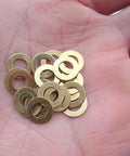 Hand holding Brass Washer Gasket Set For Knife Pivot Pins 20 Pcs Replacement, corrosion-resistant spacers for smooth blade action.