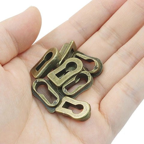 Hand holding 8Pcs Bronze Skeleton Key Covers For Furniture Keyholes Zinc Alloy Antique Style Keyhole Lids.