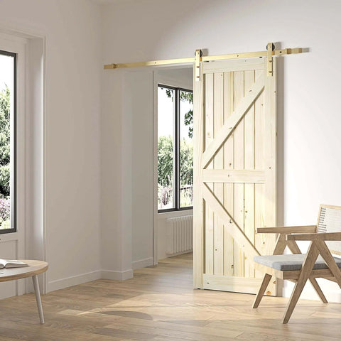 Gold Barn Door Hardware Kit With 84 Inch Track For 7 Foot Sliding Door Modern Brushed Brass Finish Includes All Mounting Hardware For One Door Adjustable Track From 39.35 Inches To 84 Inches installed on a wooden door in a bright room.