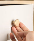 Hand installing Eight Piece Brushed Brass Cabinet Knob Set With Solid Round Hardware for drawers, 20x28mm size