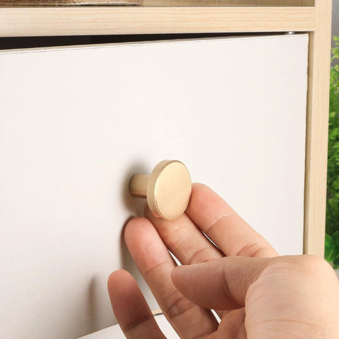 Hand installing Eight Piece Brushed Brass Cabinet Knob Set With Solid Round Hardware for drawers, 20x28mm size