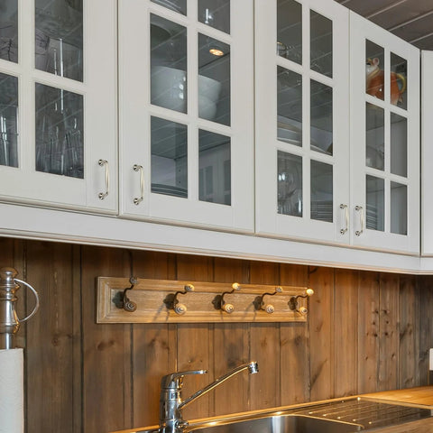 White kitchen cabinets with 20 Pack Three And Three Quarters Inch Brushed Nickel Cabinet Handles installed on glass doors above wooden backsplash.