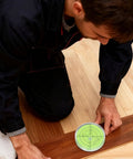 Person aligning floorboard with Five Pack Round Bubble Levels 30x10mm Mini Circular Bullseye Spirit Levels for precise alignment.