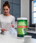 Woman using Bubble Wrap Protective Packaging 12 Inch Wide 30 Foot Roll Clear Bubble Cushions For Delicate Items Reusable Recyclable on dishes.