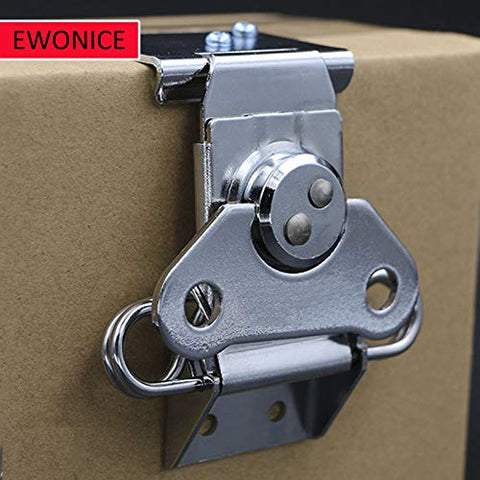 Close-up of a small butterfly twist latch with keeper plate in zinc plated steel, installed on a cardboard surface for secure closure.