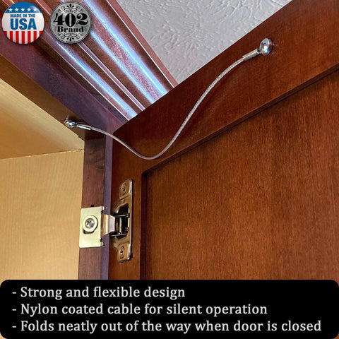 Stainless Steel Cabinet Door Restraint Kit installed on wood cabinet, showing braided cable limiting door swing. Made in USA.