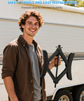 Man holding Heavy Duty X Shaped Camper RV Wheel Chock Stabilizer Two Pack With Wrench from BEBOBLY in front of a trailer.