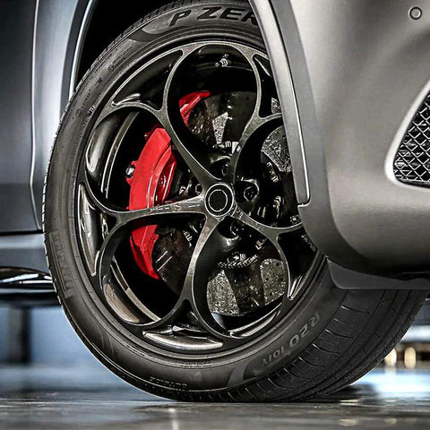 Close-up of a car wheel with a tire featuring a red brake caliper and rim, highlighting performance features.