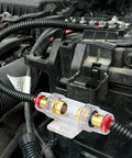 Dual Fuse Holder Kit With 100A AGU Fuses installed in car engine bay, clear polycarbonate body, gold plated terminals, 4-8 AWG wire compatible.