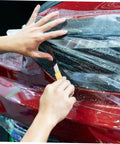 Hands installing protective film on red car headlight using cutting tool, focusing on Multifunction Home Repair Tool Kit With Handy Storage Case For DIY Projects And Maintenance All In One Handyman Set For Home Garage And Workshop Includes Essential Tools For Quick Fixes And Everyday Repairs.