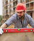 Worker using 24 inch box level with three durable acrylic vials, precise 1/16 inch ruler, wall grip, hand calibrated straightedge on site.