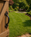 7 Inch Heavy Duty Cast Iron Barn Door Handle installed on a wooden gate in a garden setting, vintage black finish, medieval rustic design.