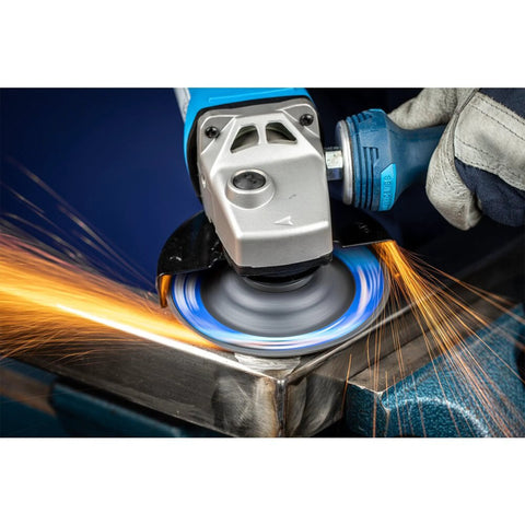 A close-up of CC Grind Robust Grinding Disc by PFERD in use, sparks flying during aggressive grinding on metal with fiberglass backing.