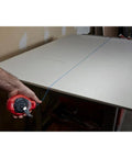 Milwaukee Chalk Line Reel Set F in use, showing 100 ft blue line marking a board for precise layout on construction project.