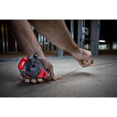 Person using Two-Pack 100 Ft Bold Line Chalk Reel With StripGuard Clutch for precise line marking on construction site floor