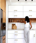 Modern kitchen with Champagne Bronze Cabinet Pulls 3 Inch Center To Center 76mm on white cabinets, woman reaching for glassware