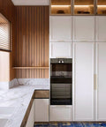 Modern kitchen with champagne bronze cabinet handles, featuring stainless steel pulls on white cabinets against a wood-paneled wall.