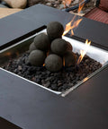 Modern fire pit with stacked Charcoal Gray 2 inch Ceramic Fire Balls - 30-Pack - Brushed Concrete Look, burning flames visible.