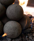 Charcoal Gray 2 inch Ceramic Fire Balls - 30-Pack - Brushed Concrete Look, Speckled in a fire pit with flames.