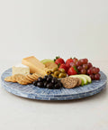 12.6 inch mother of pearl lazy susan turntable with blue starburst design featuring cheese, fruits, and crackers on a decorative tray.