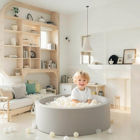 Child playing in a grey indoor ball pit with Ball Pit Balls Plastic Playballs for Baby Toddlers Kids Boys Girls Playhouse Decor Play Pool Fun Phthalate-Free BPA-Free Bath Toy White Beige Transparent,100 Balls in a cozy living room.