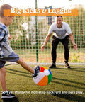 Boy kicking a rainbow beach ball towards a man on a grassy field, enjoying the 12-Pack 12" Beach Balls - Bulk Classic Beachball Inflatable Swimming Pool Toys.
