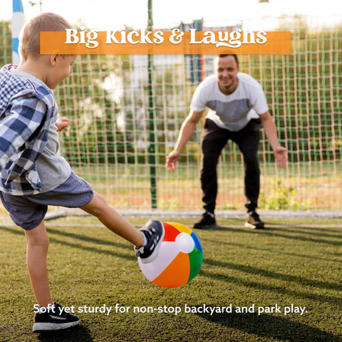 Boy kicking a rainbow beach ball towards a man on a grassy field, enjoying the 12-Pack 12" Beach Balls - Bulk Classic Beachball Inflatable Swimming Pool Toys.
