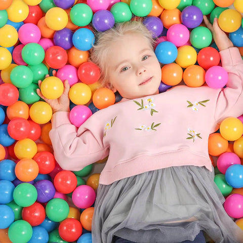 Child enjoying playtime surrounded by 50 pcs Ball Pit Balls Plastic Balls for Ball Pit, BPA Free Ocean Ball for Toddlers - 7 Colors