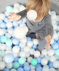Young child playing in a pile of blue and white Ball Pits Balls 500 Count Play Plastic Balls for Ball Pits Playpen BPA-Free Crush Proof.