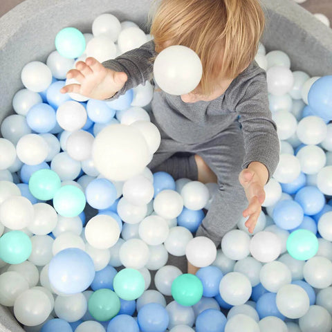 Young child playing in a pile of blue and white Ball Pits Balls 500 Count Play Plastic Balls for Ball Pits Playpen BPA-Free Crush Proof.