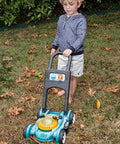 Young boy playing with toy lawnmower on grass.