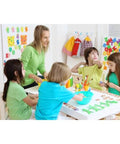 Children and teacher engaging in a craft activity at a table in a colorful classroom setting filled with educational decorations.