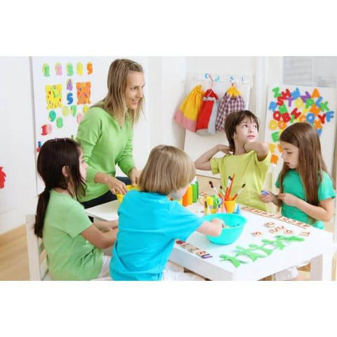 Children and teacher engaging in a craft activity at a table in a colorful classroom setting filled with educational decorations.