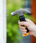 Hand using 8 ounce hammer from Bulk picture hanging kit with 600 galvanized nails to drive a nail into wood.