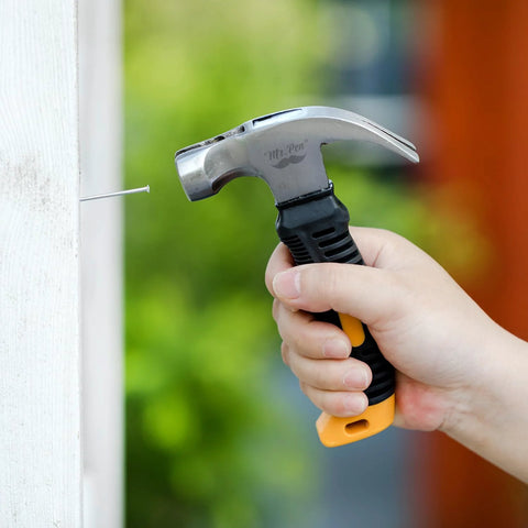 Hand using 8 ounce hammer from Bulk picture hanging kit with 600 galvanized nails to drive a nail into wood.