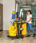Person pushing Workhorse Commercial Cleaning Cart With 3 Shelf Racks And Wheeled Design Featuring A Zippered Yellow Vinyl Bag Front Platform