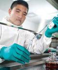 Scientist wearing A7 Cleanroom Lab Coat with High Collar and Thumb Loops, performing lab work in anti-static, low lint apparel.