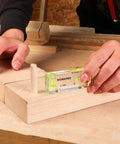 Hand using compact magnetic 3 inch mini level with two bubbles to align wooden surface showcasing shatterproof construction.