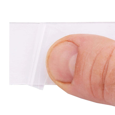 Close-up of a finger peeling Heavy Duty Clear Double Sided Mounting Tape For All Weather Indoor And Outdoor Use 1 Inch By 60 Inch Roll Transparent Adhesive.