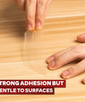 Clear Double Sided Tape Removable 1.5 Inch By 30 Yards being peeled off wood surface showing strong adhesion and gentle removal