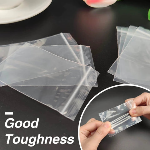 Person holding 400 Pcs Clear 3x4 Inch Jewelry Bags 2 Mil Resealable Zip Bags for Small Business Storage Candy showcasing durability.