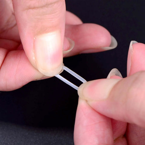 Close-up of clear rubber dampener from 200 Pieces O Ring Keyboard Dampeners For MX Switches And Mechanical Keys, being held by fingers.