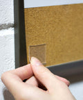 Person applying Tough And Clear Double Sided Tape Squares For Mounting, 24 Pre-Cut 1-Inch Squares to wall for indoor use