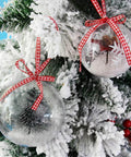 20 Pack 4-Inch Clear Plastic Fillable Ornaments Ball, decorated with ribbons and displayed on a snowy Christmas tree