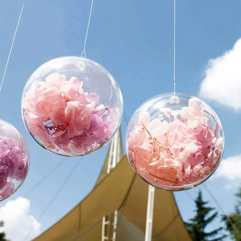 20 Pack 4-Inch Clear Plastic Fillable Ornaments Ball, hanging outside with pink flowers inside, ideal for Christmas, wedding decor.