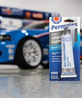 Clear RTV Silicone Adhesive Sealant, 3 Oz Tubes, Pack Of 12 in front of a blue car in a garage setting