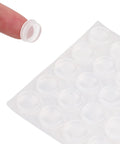 Clear Self Adhesive Cabinet Door Bumpers Set 300 Piece For Drawers And Cupboards Rubber Stoppers on sheet with finger holding one piece